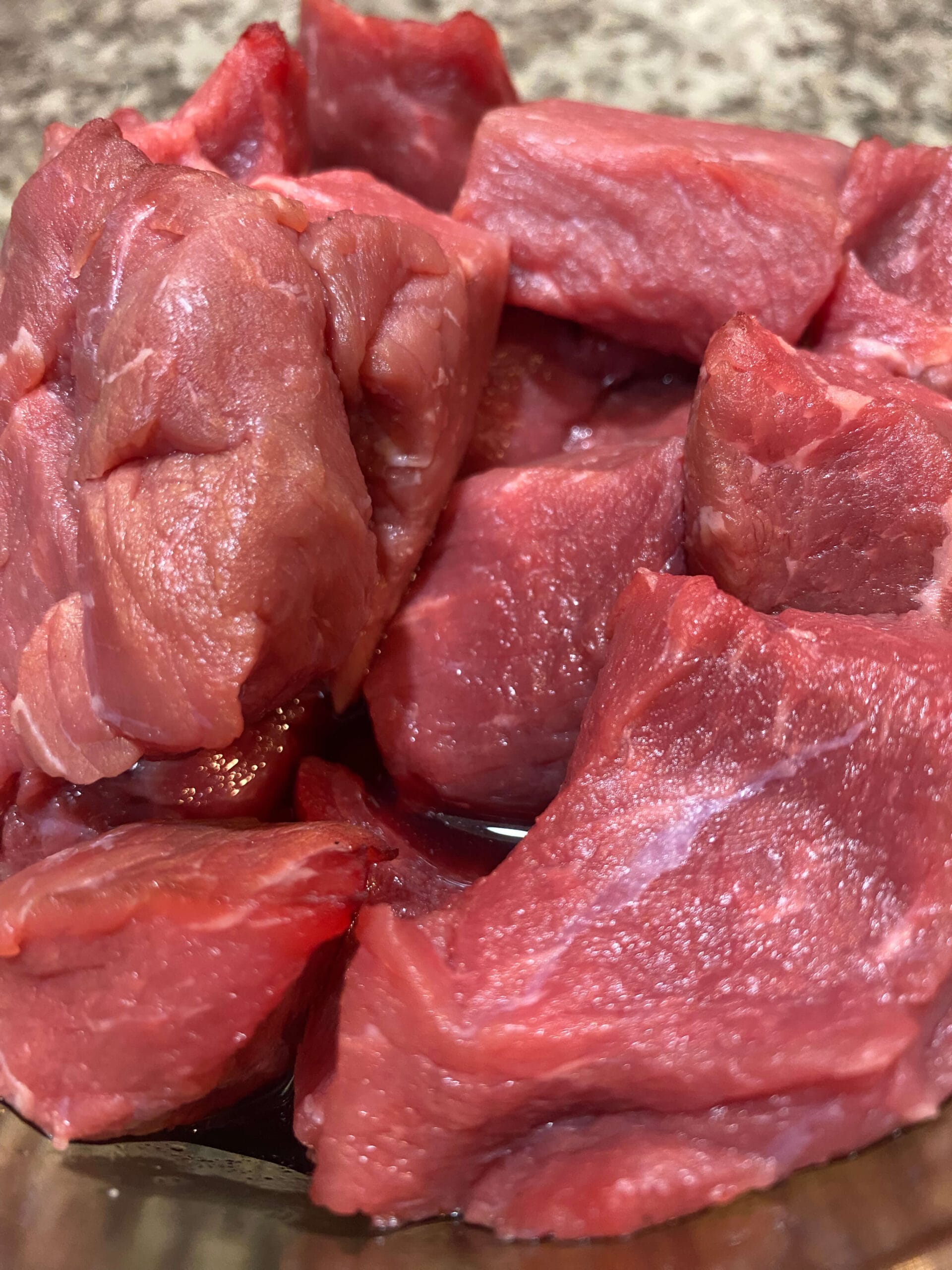 Farm-fresh grass-fed, grain-finished stew meat cubes on a rustic wooden board.
